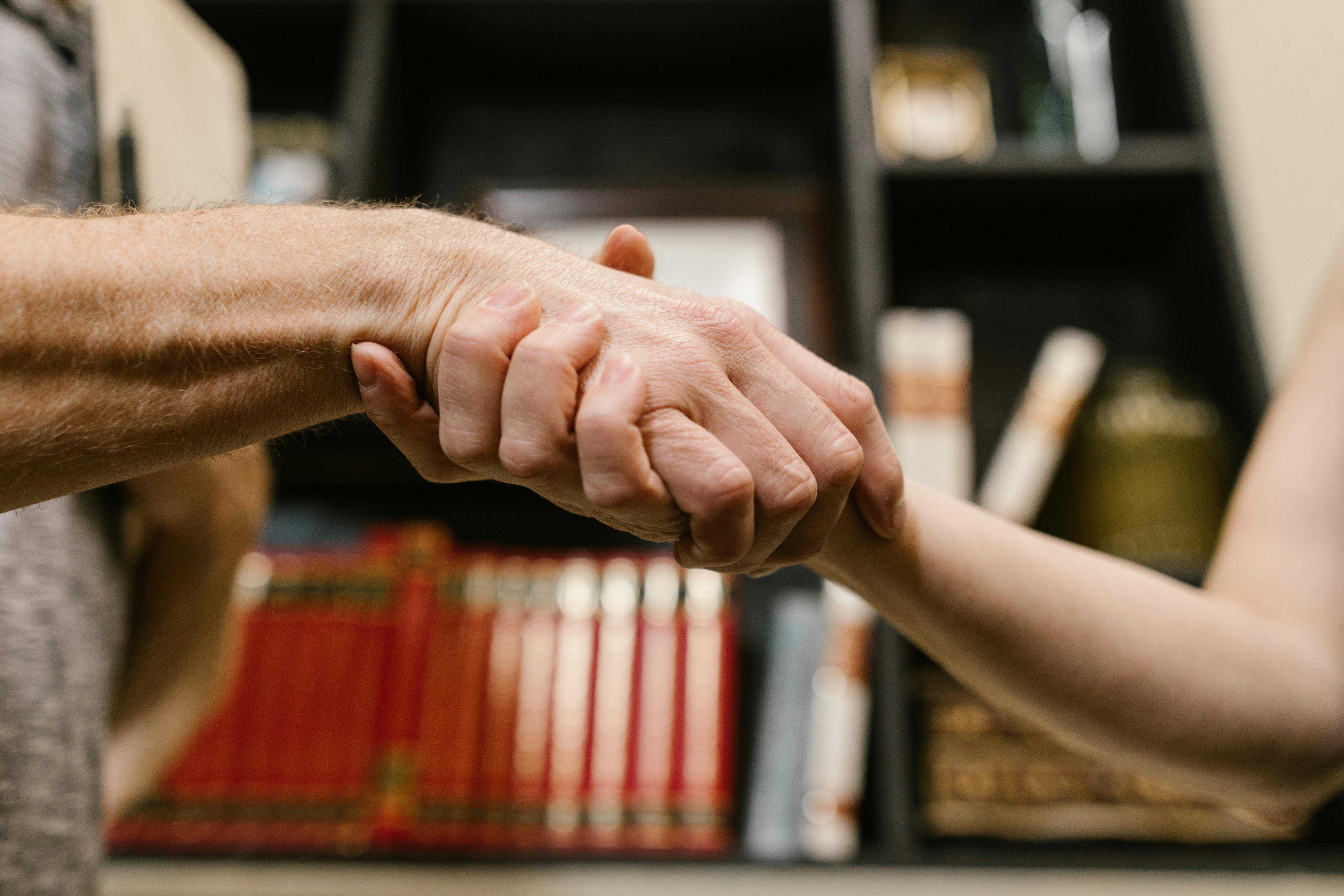 A picture of two people gripping eachothers hands.