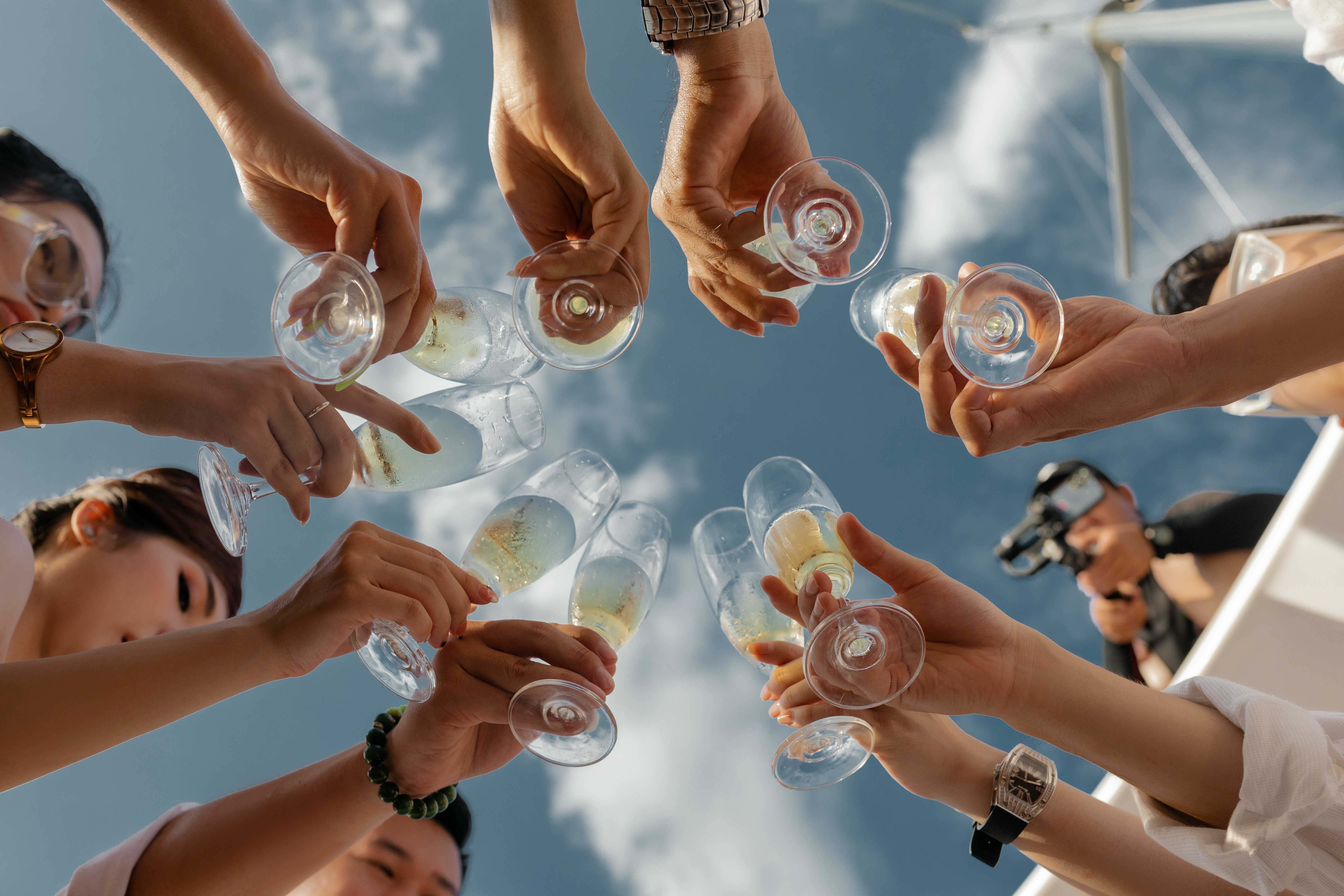 A group of people toasting champagne glasses, seen from below.